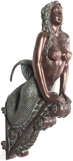 a bronze colored statue of a mermaid sitting on a wave with her arms crossed and eyes closed