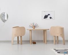 three chairs and a table in a white room with mirrors on the wall behind them