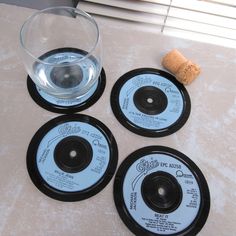 three black coasters with wine glass and cork on the table next to each other