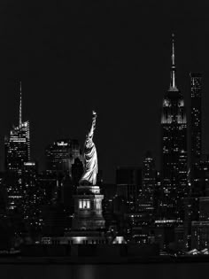 black and white photograph of the statue of liberty at night in new york city, ny