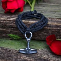 a metal anchor on a black cord with red roses in the background