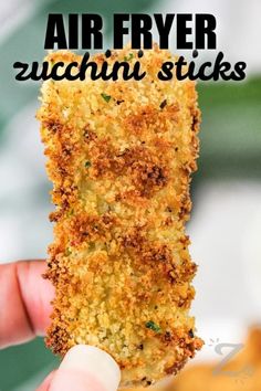 a hand holding up a piece of fried food with the words air fryer zucchini sticks above it