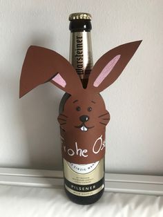 a bottle that has some kind of paper rabbit on it's head in front of a wall