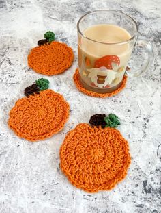 three crocheted pumpkin coasters next to a cup of coffee