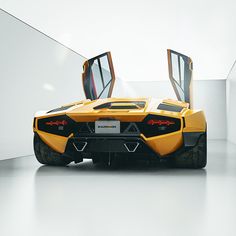 a yellow and black sports car parked in a white room with its doors open to reveal the interior