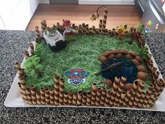 a birthday cake made to look like a castle with lots of green grass and toys