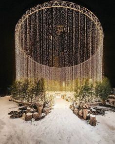 a large circular structure with lights hanging from it's sides in the snow at night