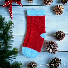 a red and blue knitted stocking with pine cones on the side next to it