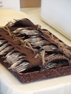 forks and spoons are placed in a woven basket on a tablecloth covered tray