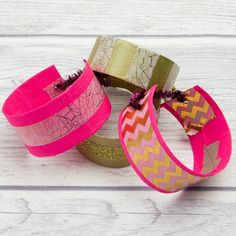 three different colored bracelets sitting on top of a white wooden table next to each other