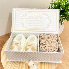 a box that has some baby shoes in it on a table next to a potted plant