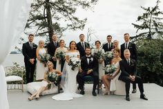 a large group of people posing for a photo on a deck with white drapes