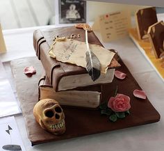 a cake made to look like an old book with a feather and skull on top