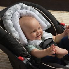 a baby sitting in a stroller smiling at the camera