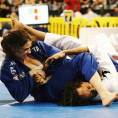 two people on the ground during a competition with one person holding another in the air