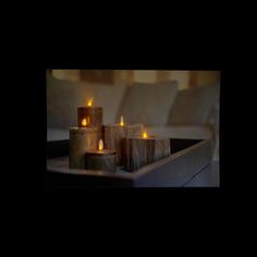 three lit candles sitting on top of a table next to white couches and pillows