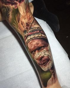 an old man's leg with tattoos on it and his face painted in red