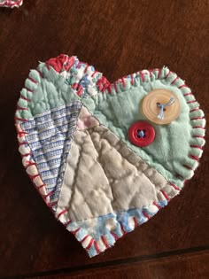 a close up of a heart shaped object on a wooden table with buttons and thread