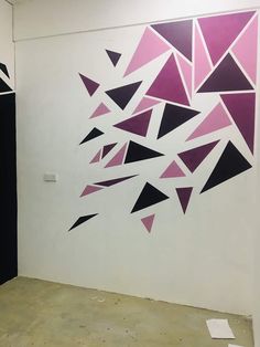 an abstract painting on the wall with black and pink triangles painted on it's walls