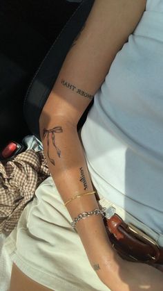 a woman sitting in the back seat of a car holding onto her arm with tattoos on it