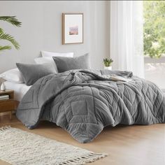 a bed with grey comforter and pillows in a room