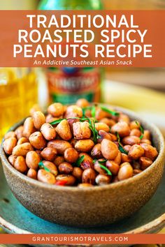 a wooden bowl filled with roasted peanuts and garnished with herbs next to a bottle of booze