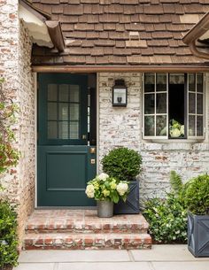 the front door of a brick house with two planters