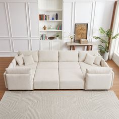 a living room with a large white sectional couch and rugs on the hardwood floor