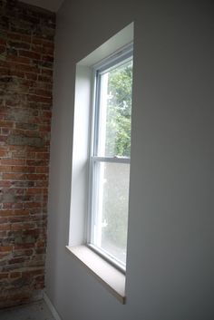 an empty room with a brick wall and window