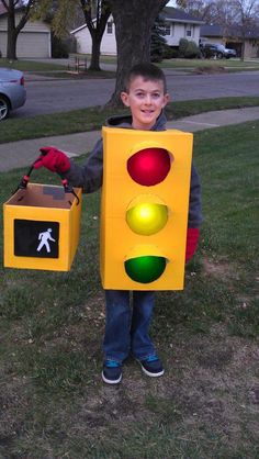 a young boy dressed as a traffic light holding a box with a walk signal on it