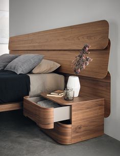 a bed with a wooden headboard and night stand next to it on concrete flooring