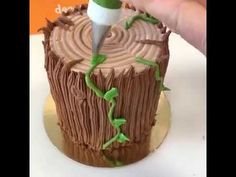 a person cutting into a cake that looks like a tree stump with green leaves on it