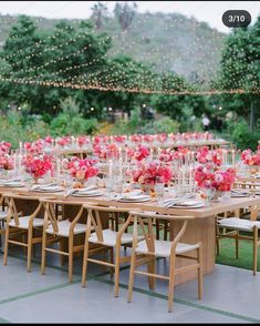 a long table set up with pink flowers and candles for an outdoor wedding reception in the mountains