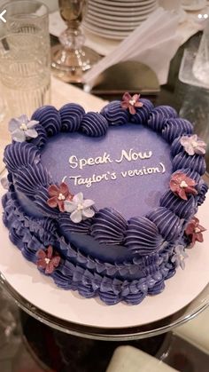 a heart shaped cake with purple frosting and flowers on it that says speak now, taylor's version