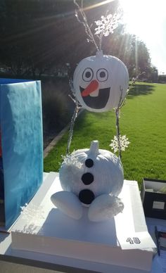 a snowman made out of plastic sitting on top of a white box in the grass