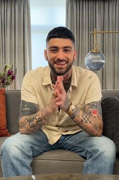 a man with tattoos sitting on a couch