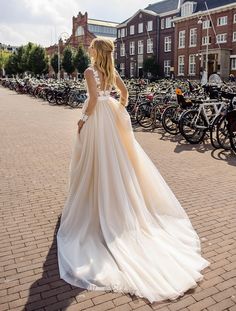 a woman in a wedding dress is walking down the street with bicycles parked behind her