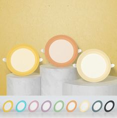 there are four different colored circles on the top of three pedestals in front of a yellow wall