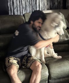 a man sitting on top of a couch holding a dog