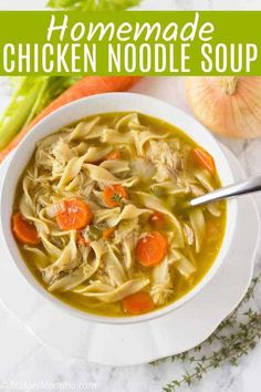 homemade chicken noodle soup in a white bowl with carrots and celery