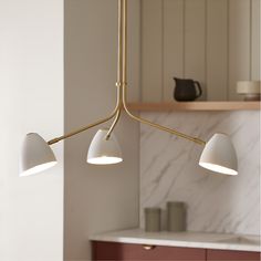 three lights are hanging from the ceiling in a kitchen with marble counter tops and cabinets