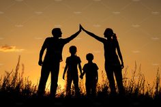 a family silhouetted against the sunset with their hands together