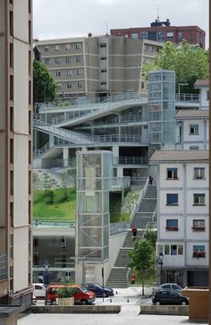 a building with stairs and cars parked in the parking lot next to it on a cloudy day