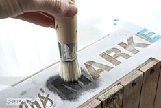 someone is using a brush to paint the letters on a wooden sign that says army