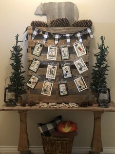 a wooden table topped with pictures and pine trees next to a basket filled with pine cones