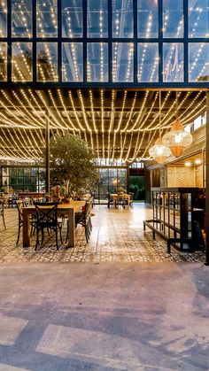 an outdoor dining area with lights on the ceiling and tables set up for four people