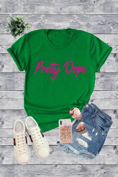 a green shirt that says pretty dope next to some jeans and shoes on a wooden surface