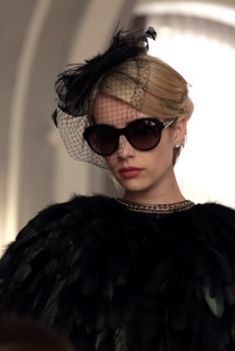 a woman wearing sunglasses and a hat with feathers