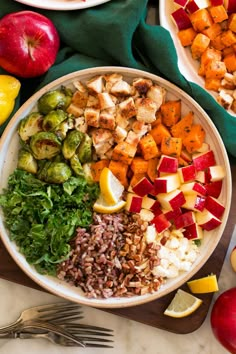 a bowl filled with rice, vegetables and meat next to two plates of food on a table