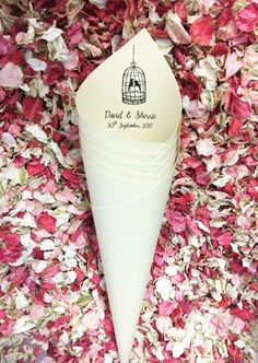 a paper cone with a birdcage on it is surrounded by pink and white flowers